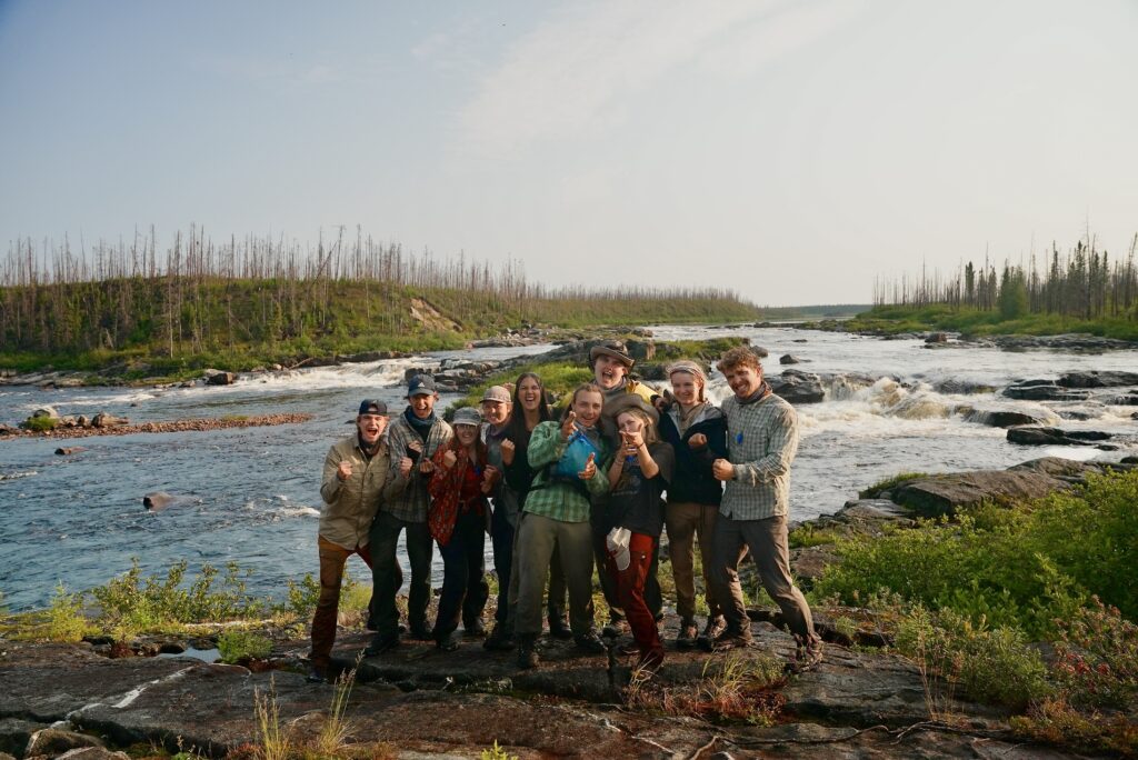 Group posing by a scenic riverside.
